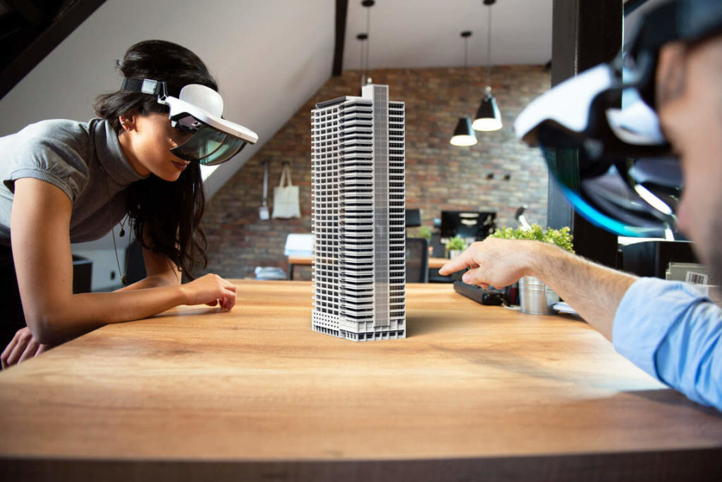homem e mulher com óculos de realidade virtual em frente a maquete de edifíco
