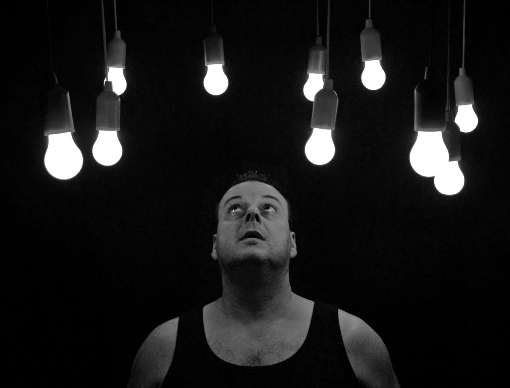 Homem olhando para lâmpadas acesas acima da sua cabeça
