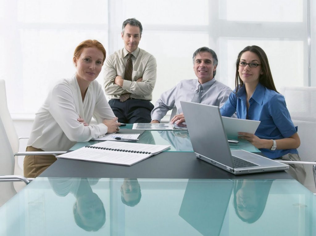 homens e mulheres sentados à mesa com papéis e notebook