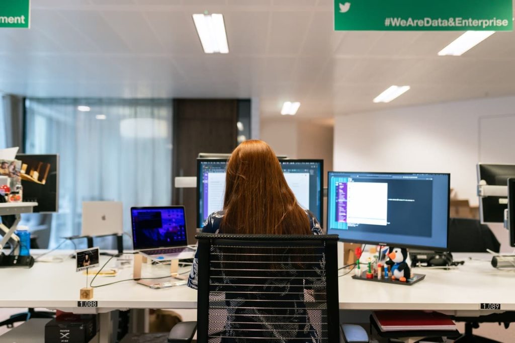 Mulher sentada em frente a computadores no escritório
