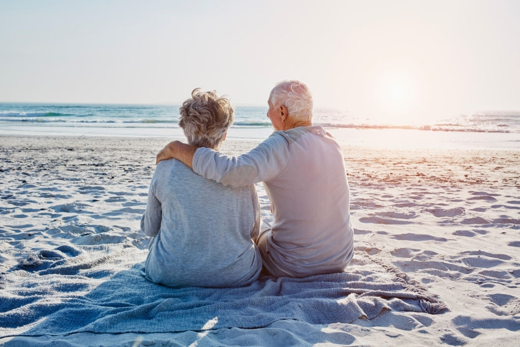 casal de idosos sentado na praia